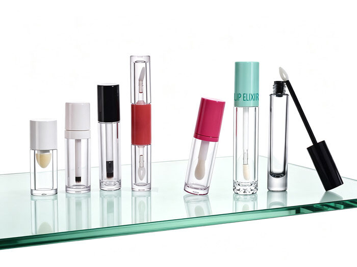 empty lip gloss tubes and containers with different applicator and caps standing on a glass podium